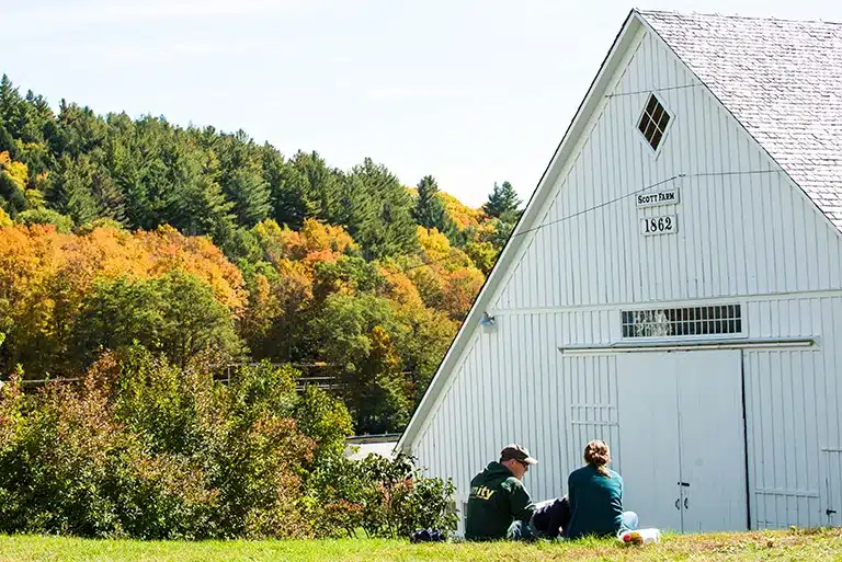 A couple relaxes on the lawn in front of the 1862 building at Scott Farm